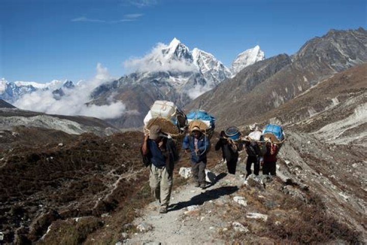 How are porters and Sherpas important to mountain climbers?
